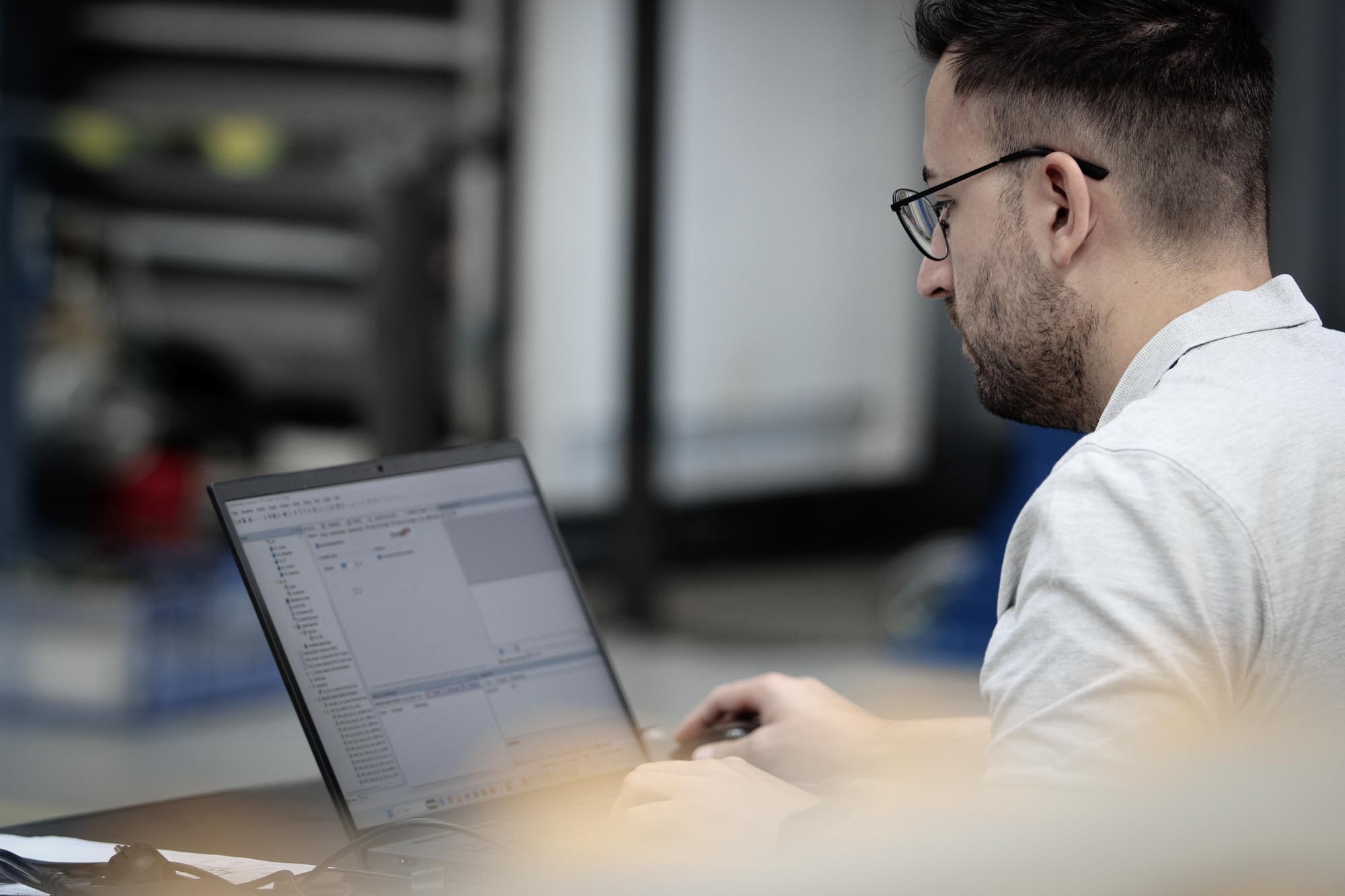 Mitarbeiter aus dem Engineering sitzt mit Laptop auf einem Tisch